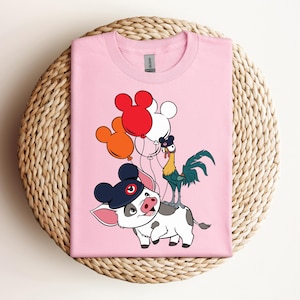 Op de afbeelding: Zachtroze T-shirt met een cartoonillustratie van een varken met een Mickey Mouse-hoed, een haan en rode, witte en oranje ballonnen. Het shirt is gemaakt van een zacht materiaal en is geschikt voor vrijetijdskleding.