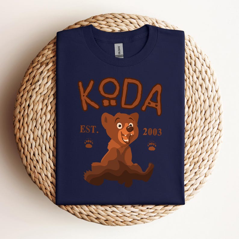 May include: A navy blue t-shirt with a cartoon bear and the text "KODA EST. 2003".