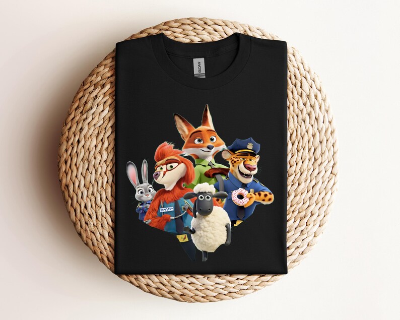 May include: Black t-shirt featuring a colorful graphic of characters from the animated movie Zootopia. The design includes a fox, a rabbit, a sheep, a cheetah, and other characters. The shirt is displayed on a woven, circular surface.
