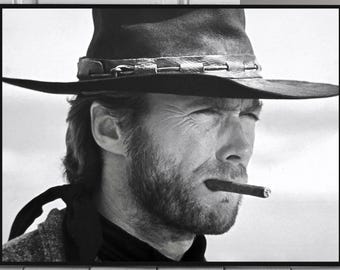 May include: Black and white portrait of a man wearing a cowboy hat and smoking a cigar. The man has a beard and a serious expression on his face.