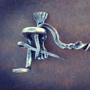 May include: A silver metal door latch with a twisted design and decorative finials. The latch is attached to a metal surface.