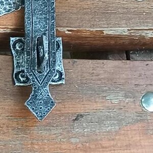 Könnte beinhalten: Drei verzierte Metall-Türriegel mit komplizierten Designs. Die Riegel sind silberfarben und haben ein rustikales, antikes Aussehen.