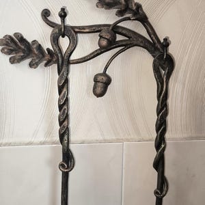 Peut inclure: Objet en m&eacute;tal forg&eacute; &agrave; la main avec un motif de feuilles de ch&ecirc;ne et de glands. La pi&egrave;ce a une finition bronze antique fonc&eacute;. Les colonnes en m&eacute;tal torsad&eacute; soutiennent le dessus d&eacute;coratif, cr&eacute;ant une esth&eacute;tique unique inspir&eacute;e de la nature.