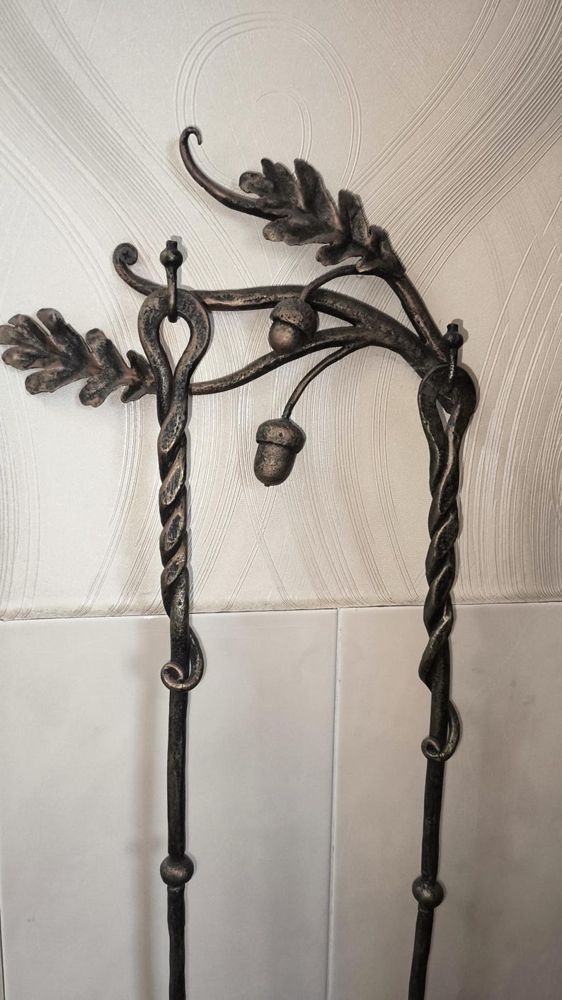 Peut inclure: Objet en m&eacute;tal forg&eacute; &agrave; la main avec un motif de feuilles de ch&ecirc;ne et de glands. La pi&egrave;ce a une finition bronze antique fonc&eacute;. Les colonnes en m&eacute;tal torsad&eacute; soutiennent le dessus d&eacute;coratif, cr&eacute;ant une esth&eacute;tique unique inspir&eacute;e de la nature.