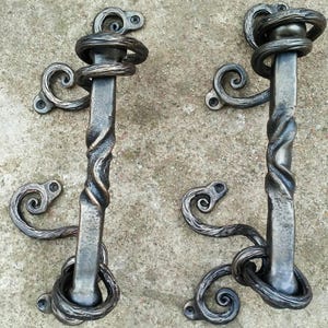 May include: A white ceramic mug with a black handle and the text "But First, Coffee" in a bold, black font. The mug is set against a blurred background, suggesting a cozy setting.