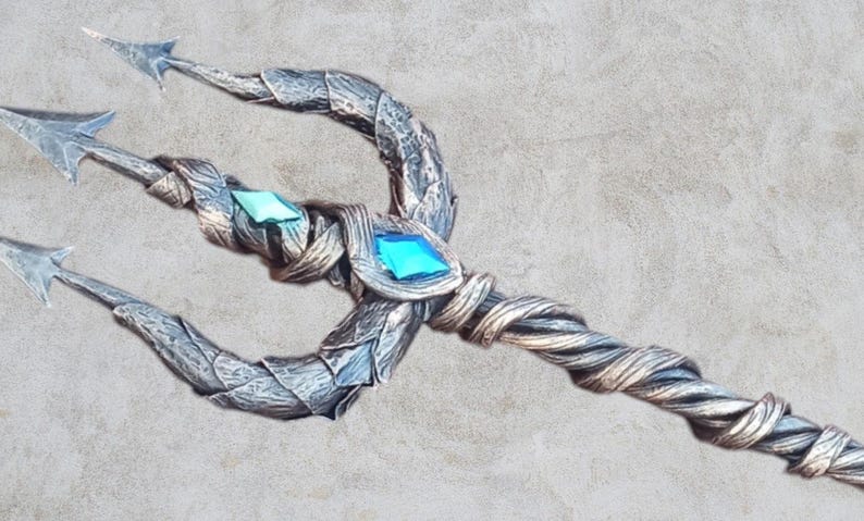 May include: A silver and gold trident with a twisted handle and two blue and green gemstones.