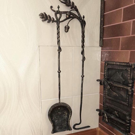 A blacksmith hammered an entire oak-forest scene into wrought iron fireplace tools — functional hearth hardware that looks like it belongs in a manor house.