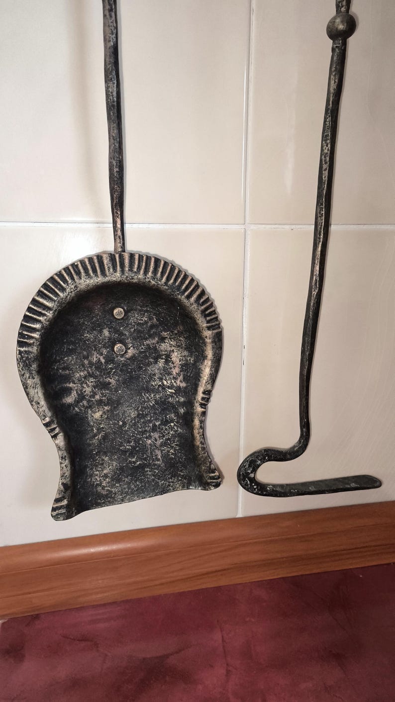 Peut inclure: Un ensemble d'outils de chemin&eacute;e, comprenant une pelle et un tisonnier, en m&eacute;tal fonc&eacute; avec une finition vieillie. La pelle a une cuill&egrave;re arrondie avec un bord d&eacute;coratif. Le tisonnier a une extr&eacute;mit&eacute; incurv&eacute;e.