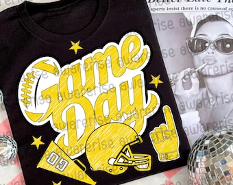 May include: Black t-shirt with a yellow "Game Day" graphic. The design includes a football, helmet, megaphone, and a hand with the number one. Several yellow stars are scattered around the design.