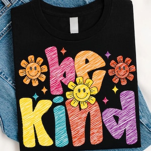 以下が含まれることがあります： カラフルなレトロスタイルの文字で「be kind」と書かれた黒いTシャツ。デザインには、笑顔の太陽と星のグラフィックが含まれています。このシャツは柔らかい素材で作られています。