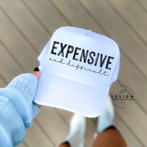 Könnte beinhalten: Weiße Trucker-Kappe mit schwarzem Text, der "EXPENSIVE and difficult" lautet.