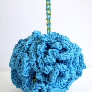 Può includere: Un pompon di uncinetto blu con uno spago verde e bianco appeso.