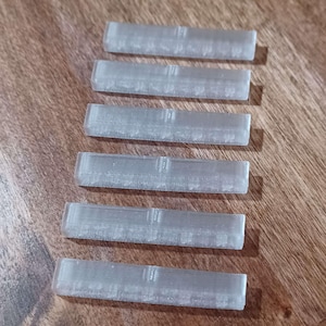 May include: Six clear plastic rulers, each with a different measurement scale, are arranged vertically on a wooden surface.