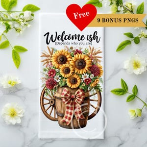 May include: White kitchen towel featuring a floral arrangement of sunflowers, dahlias, and wheat in a wooden barrel wagon. The towel has the text "Welcome ish (Depends who you are)" and a red heart with the word "Free".