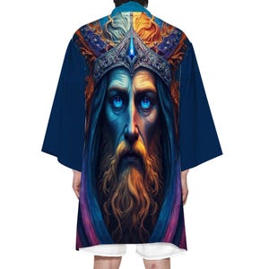 May include: A navy blue kimono-style robe featuring a detailed illustration of a bearded figure wearing a crown with a blue gemstone. The artwork has a fantasy theme with vibrant colors and intricate details. The robe has wide sleeves.