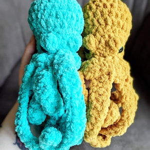 May include: Two plush octopus toys. One is a vibrant turquoise, the other a warm golden yellow. Both have textured, fluffy bodies and rounded heads with small, dark eyes. The tentacles are curled, giving them a playful appearance.