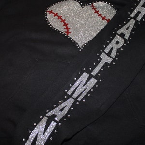 May include: Black hoodie with a silver glitter heart-shaped baseball design and the word "HEART" spelled out in silver glitter on the sleeve.