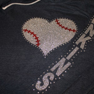 May include: A dark blue hoodie with a silver glitter baseball heart and the word "SKINZ" in silver glitter on the sleeve.