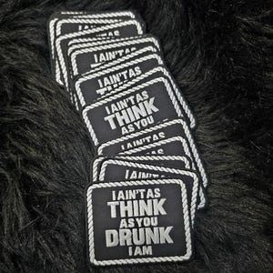 Könnte beinhalten: Ein Stapel rechteckiger, schwarzer, bestickter Aufnäher mit einem weißen Rand in Seiloptik. Jeder Aufnäher zeigt den weißen Text I AIN'T AS THINK AS YOU DRUNK I AM in fünf Zeilen, wobei die Wörter THINK und DRUNK in größerer Fettschrift stehen.