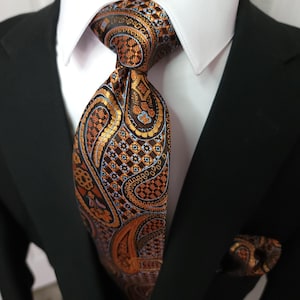 Conjunto de lujo de corbata, pañuelo de bolsillo y gemelos de seda con estampado paisley en color naranja quemado.
