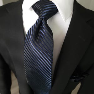 Set composto da cravatta, fazzoletto da taschino e gemelli in seta a righe blu navy e nere.