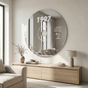 May include: A large, round mirror designed to resemble a CD, mounted on a wall. The mirror features the year "1997" and the words "Compact Disc Digital Audio" with a palm tree graphic. The mirror reflects a living room with a sofa and wooden furniture.