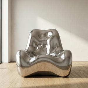 May include: A modern, sculptural chair with a reflective, metallic silver finish. The chair has a unique, flowing design with rounded edges and a low profile. It sits on a wooden floor in a well-lit room.