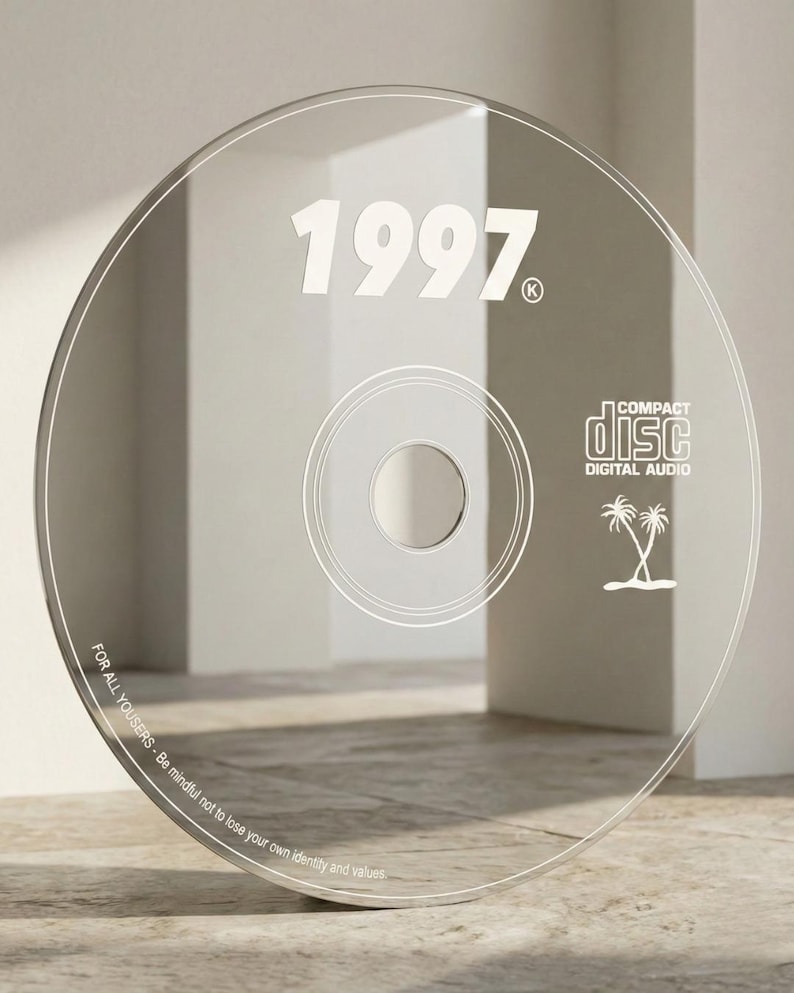 May include: Clear CD with the year "1997" in white, along with the text "COMPACT DISC DIGITAL AUDIO" and a palm tree graphic. The edge of the disc has the text "FOR ALL YOUSERS - Be mindful not to lose your own identity and values."