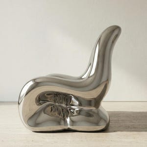 May include: A modern, sculptural chair with a polished, reflective silver finish. The chair has an organic, flowing form, with a rounded base and a curved backrest. The design is minimalist and contemporary, suitable for interior decor.