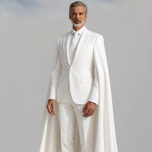 May include: A formal white suit with a matching cape. The suit includes a blazer, trousers, and a tie. The cape flows down to the floor. The person is wearing white boots. The background is a solid light gray.
