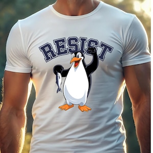 May include: White t-shirt with a cartoon penguin holding a fish and the word "RESIST" in blue letters.