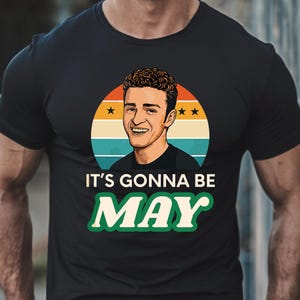 May include: A black t-shirt featuring a retro-style graphic of a man with the text "It's gonna be May" in green letters.
