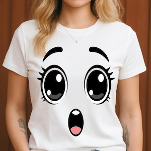 Puede incluir: Camiseta blanca con un dise&ntilde;o de cara de dibujos animados sorprendida. El gr&aacute;fico incluye ojos negros grandes con reflejos blancos, pesta&ntilde;as negras y una boca abierta sorprendida con el interior rosa. La camiseta la lleva una persona.