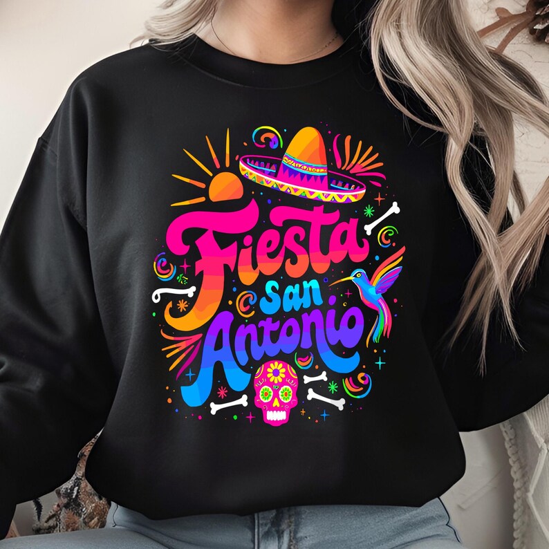 May include: Black sweatshirt with a colorful graphic design featuring the text "Fiesta San Antonio" with a sombrero, a hummingbird, and a sugar skull.