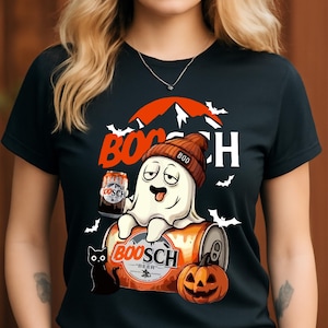 Op de afbeelding: Zwart T-shirt met een Halloween-thema. Het heeft een cartoongeest met een muts, zittend op een bierblikje met het opschrift "BOOSCH BEER". Een pompoen, zwarte kat, vleermuizen en bergen maken het ontwerp compleet.