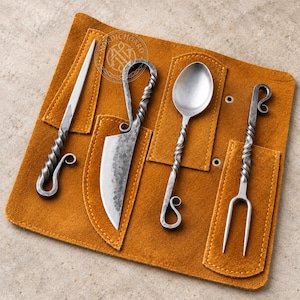 May include: A set of four hand-forged metal utensils including a pointed tool, a knife, a spoon, and a two-pronged fork, each featuring a twisted handle with a curled end. The utensils are arranged in a tan suede leather roll with stitched pockets.