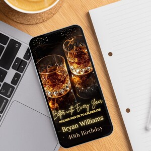 Peut inclure: Un smartphone affiche une invitation d'anniversaire avec deux verres de liquide ambr&eacute;. L'invitation dit "Better with Every Year" et invite les invit&eacute;s &agrave; c&eacute;l&eacute;brer le 40e anniversaire de Bryan Williams. Le t&eacute;l&eacute;phone est sur un bureau en bois &agrave; c&ocirc;t&eacute; d'un ordinateur portable et d'un bloc-notes.