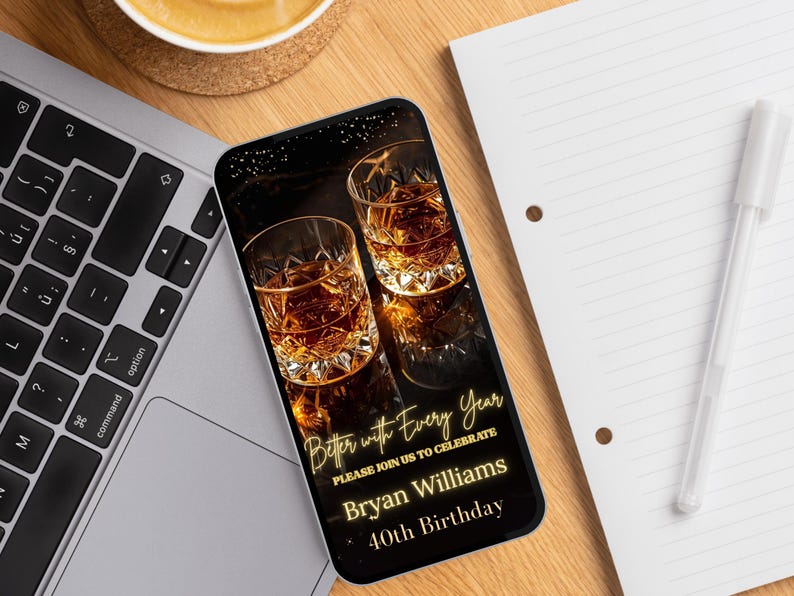 Peut inclure: Un smartphone affiche une invitation d'anniversaire avec deux verres de liquide ambr&eacute;. L'invitation dit "Better with Every Year" et invite les invit&eacute;s &agrave; c&eacute;l&eacute;brer le 40e anniversaire de Bryan Williams. Le t&eacute;l&eacute;phone est sur un bureau en bois &agrave; c&ocirc;t&eacute; d'un ordinateur portable et d'un bloc-notes.
