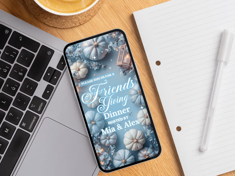 May include: A smartphone displays a Friendsgiving dinner invitation. The invitation features a light blue background with white and blue pumpkins, floral accents, and the text "PLEASE JOIN US FOR A Friends Giving Dinner HOSTED BY Mia & Alex."