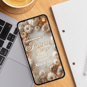 May include: A smartphone displays a Friendsgiving dinner invitation. The design features white and gold pumpkins, floral accents, and the text "Please join us for a Friendsgiving Dinner hosted by Mia & Alex."