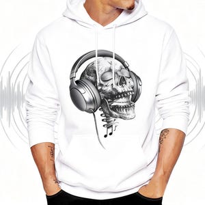 May include: White hoodie featuring a detailed grayscale illustration of a skull wearing large headphones. The design includes musical notes and a stylized sound wave pattern, creating a unique graphic.