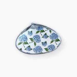 May include: A white ceramic seashell dish with a blue and green hydrangea floral pattern.