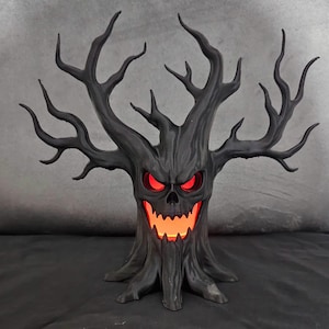 Könnte beinhalten: Schwarze, gruselige Halloween-Dekoration in Form eines Baumes mit einem geschnitzten Gesicht und leuchtenden roten Augen und Mund. Der Baum hat viele Äste und ein strukturiertes Rinden-Aussehen. Das Licht im Inneren des Baumes verleiht ihm ein bedrohliches Aussehen.
