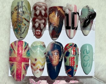 May include: A set of ten artificial nails with various designs. The designs include images of a person, bows, the Union Jack, and the text "LONDON" and "eos". The nails are in various colors, including pink, blue, and red.