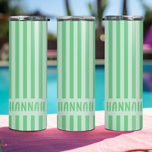 May include: Three cylindrical tumblers with lids, each featuring a vertical striped pattern in alternating shades of light green and mint. The name HANNAH is printed in a bold, sans-serif font across the lower section of each tumbler.
