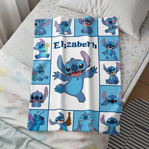 May include: A blue and white blanket featuring the character Stitch from Lilo & Stitch. The blanket has a grid pattern with various Stitch poses and the name "Elizabeth" in the center. The blanket is made of a soft material.