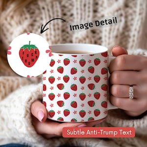 May include: White ceramic mug with a strawberry pattern and the text "FUCK TRUMP" inside a strawberry graphic. The mug also has a pattern of red strawberries and small white flowers.