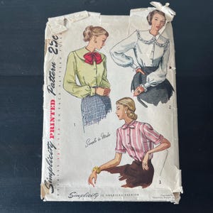 May include: Vintage Simplicity sewing pattern for a blouse with a Peter Pan collar. The pattern shows three different styles of blouses, one with a bow, one with a lace collar, and one with a striped pattern. The pattern is printed on paper and has a price of 25 cents.