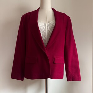 Pu&ograve; includere: Un blazer rosso scuro con revers a lancia e due tasche anteriori. Il blazer &egrave; esposto su un manichino, mettendo in risalto la sua vestibilit&agrave; su misura e il design classico. Il capo ha maniche lunghe e una chiusura con un solo bottone.