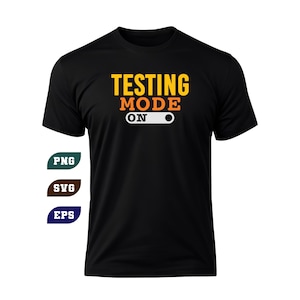 May include: Black t-shirt with the text "TESTING MODE ON" in orange and yellow. The design includes a white and gray switch graphic. The shirt is a classic crew neck style.